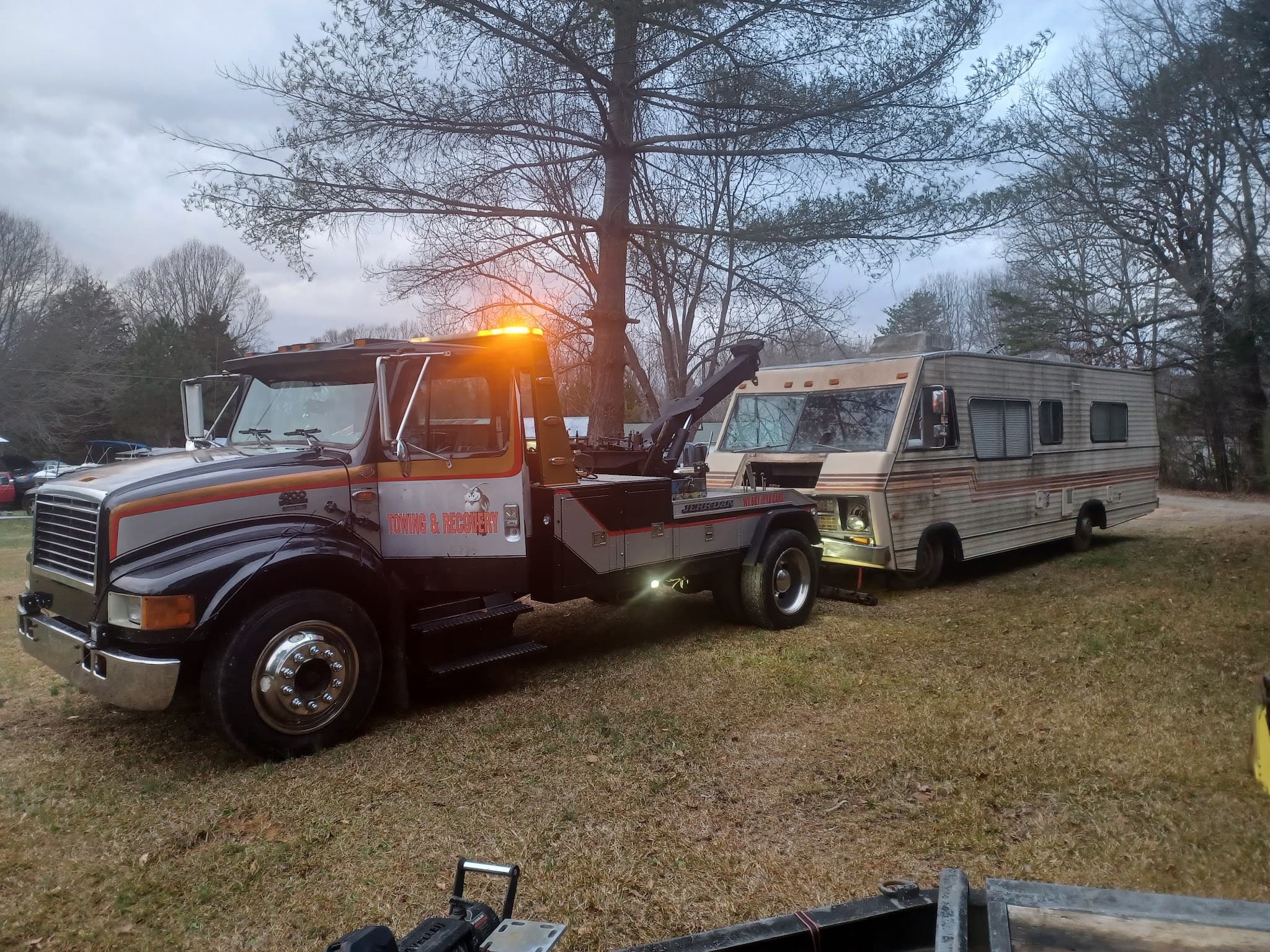 Goodfellas Towing wrecker recovering an RV at dusk in the Charlotte metro
